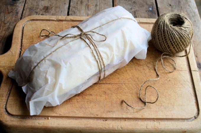 Method: 1. Cut the loaf of bread in half as seen in the photos. 2. Spread both halves of the bread with the butter and then layer up the ingredients on one half of the bread loaf in the order listed – see the photos. 3. Place the lid on top of the filling and then wrap in greaseproof paper and tie with some string. 4. Place some heavy books or weights on top and leave for at least 12 to 24 hours, in a cool place. 5. Serve in slices.