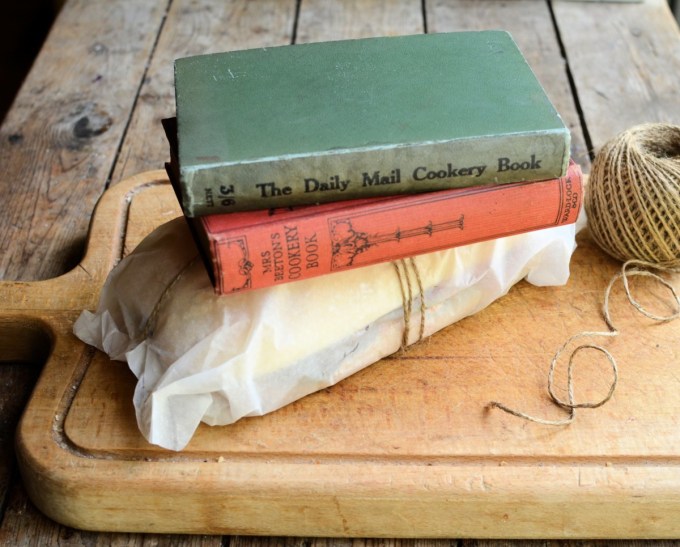 Method: 1. Cut the loaf of bread in half as seen in the photos. 2. Spread both halves of the bread with the butter and then layer up the ingredients on one half of the bread loaf in the order listed – see the photos. 3. Place the lid on top of the filling and then wrap in greaseproof paper and tie with some string. 4. Place some heavy books or weights on top and leave for at least 12 to 24 hours, in a cool place. 5. Serve in slices.